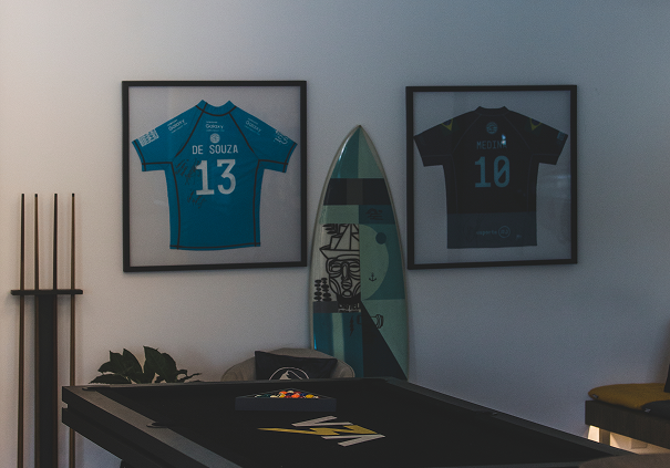 Camisetas de times emolduradas na parede do escritório da V3A.